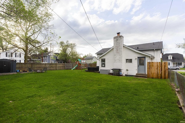 view of yard with entry steps, a fenced backyard, and a playground