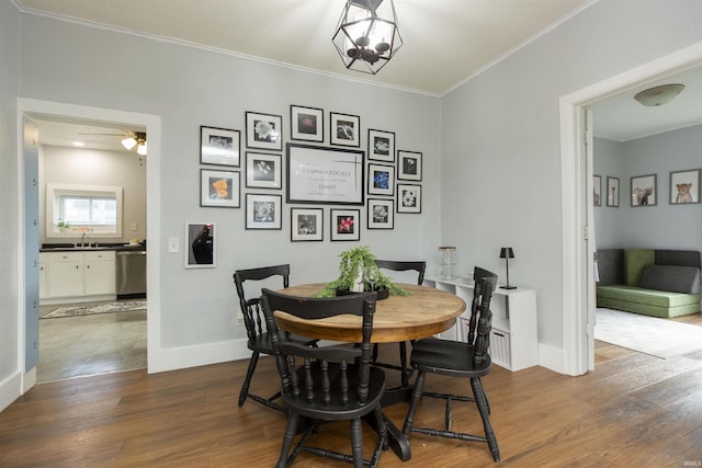 dining room featuring crown molding, baseboards, a ceiling fan, and dark wood finished floors