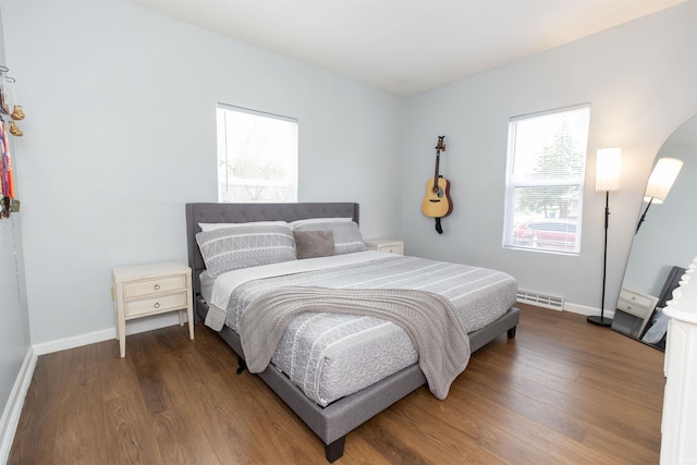 bedroom featuring arched walkways, baseboards, visible vents, and wood finished floors