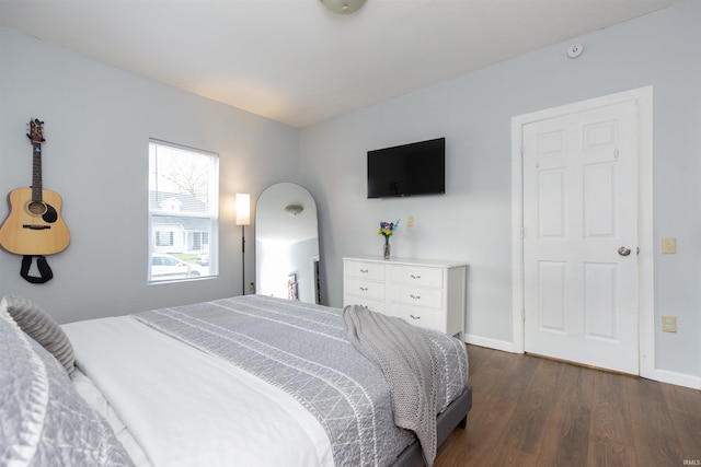 bedroom featuring baseboards and dark wood-style flooring