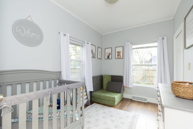 bedroom with visible vents, a crib, crown molding, and wood finished floors
