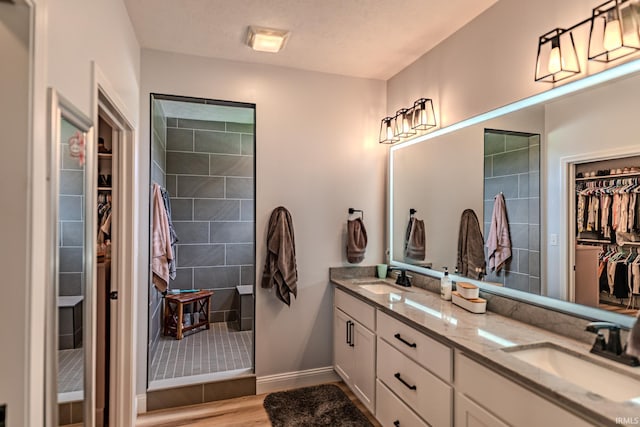 4663 Beringer Dr, Lafayette, IN 47909 - full bath featuring a sink, tiled shower, double vanity, a walk in closet, and wood finished floors