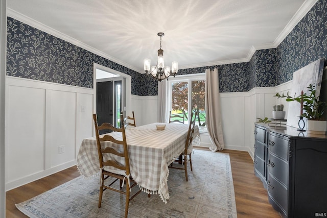 dining area featuring ornamental molding, wainscoting, a chandelier, and wallpapered walls