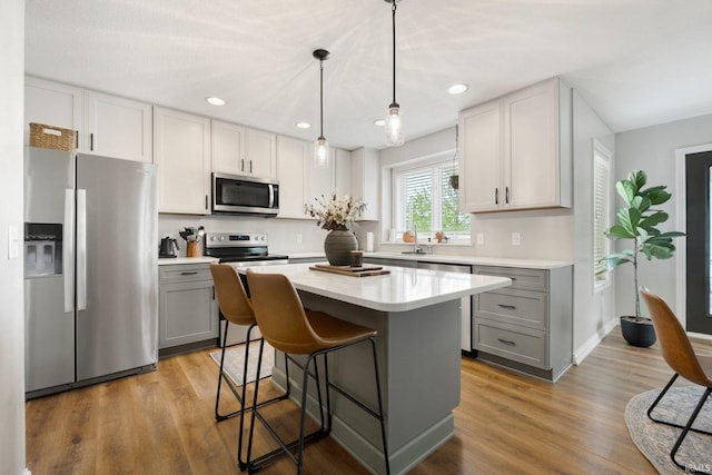 kitchen featuring a center island, light countertops, gray cabinets, and stainless steel appliances