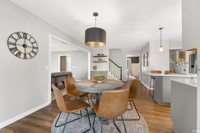 dining space with baseboards, stairs, and wood finished floors