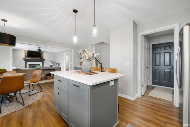 kitchen featuring freestanding refrigerator, gray cabinetry, a glass covered fireplace, and wood finished floors