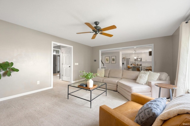 living room featuring a ceiling fan, baseboards, and light carpet