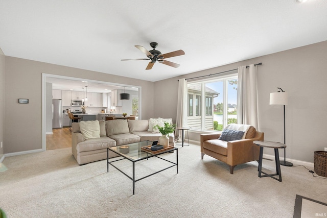 living room with baseboards, ceiling fan, and light carpet