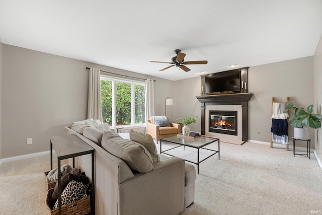 carpeted living room featuring a glass covered fireplace, baseboards, and a ceiling fan