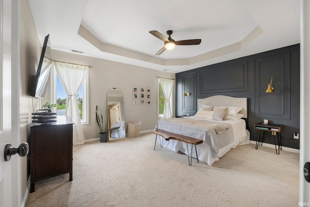 bedroom featuring visible vents, baseboards, ceiling fan, light colored carpet, and a raised ceiling
