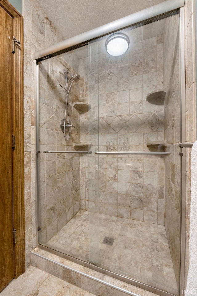 full bath featuring a textured ceiling and a stall shower