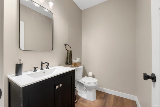 bathroom with baseboards, vanity, toilet, and wood finished floors
