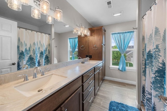 full bathroom with a sink, baseboards, double vanity, and visible vents