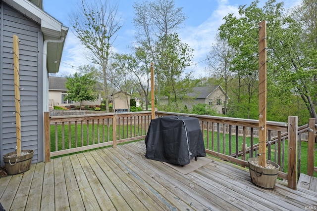 wooden terrace featuring a yard and a grill