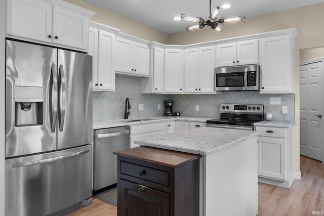 kitchen with a kitchen island, appliances with stainless steel finishes, light wood-type flooring, a sink, and white cabinetry
