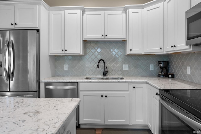 kitchen with white cabinets, appliances with stainless steel finishes, decorative backsplash, and a sink