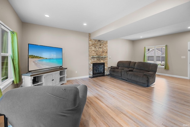 living room featuring baseboards, a fireplace, recessed lighting, and wood finished floors