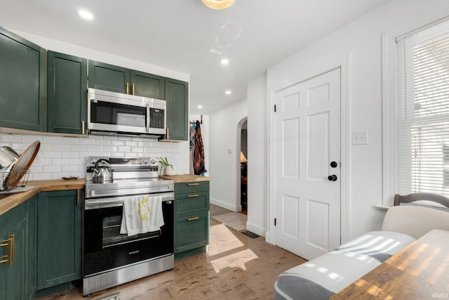 2819 Witchwood Dr, Fort Wayne, IN 46809 - kitchen featuring appliances with stainless steel finishes, arched walkways, green cabinetry, and butcher block counters