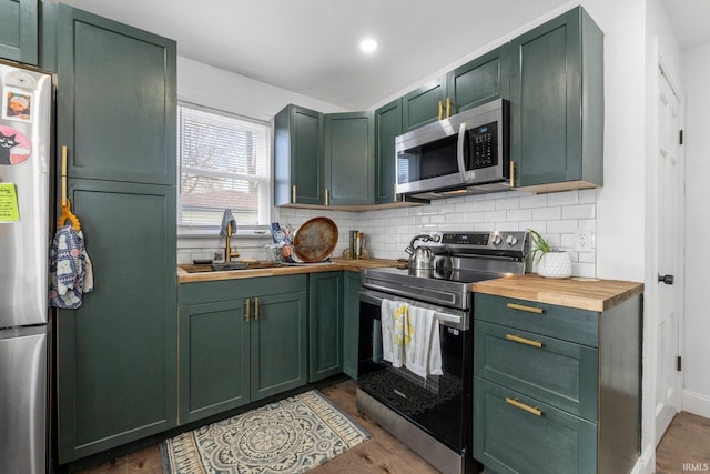 2819 Witchwood Dr, Fort Wayne, IN 46809 - kitchen featuring wood finished floors, butcher block countertops, green cabinetry, a sink, and stainless steel appliances