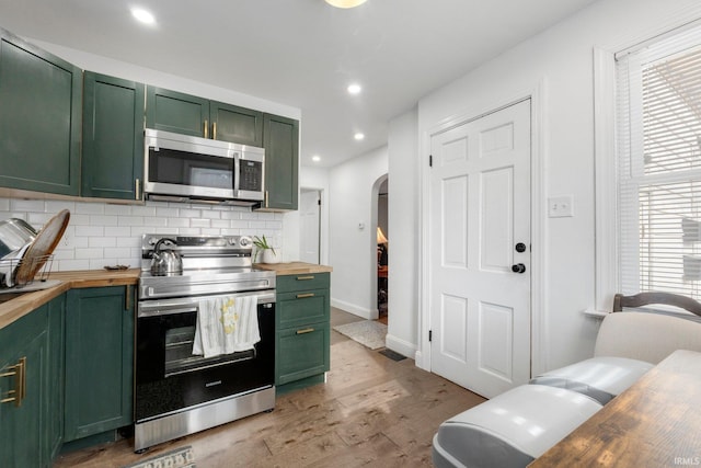2819 Witchwood Dr, Fort Wayne, IN 46809 - kitchen featuring wooden counters, green cabinetry, tasteful backsplash, arched walkways, and appliances with stainless steel finishes