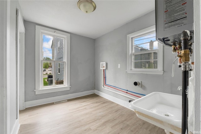 bathroom featuring baseboards, visible vents, wood finished floors, and water heater