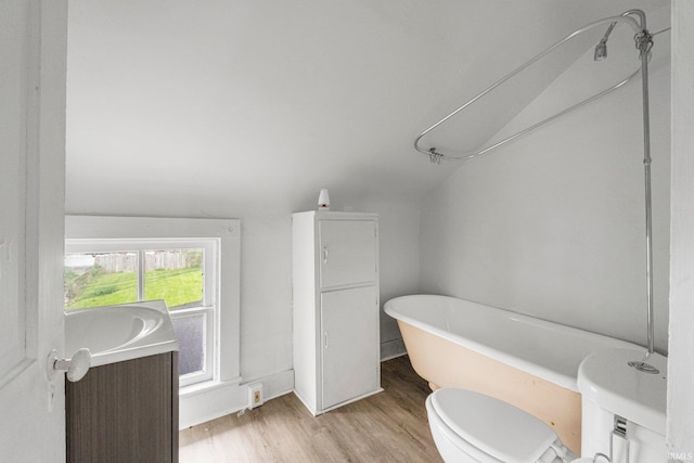 full bathroom featuring toilet, a freestanding tub, and wood finished floors