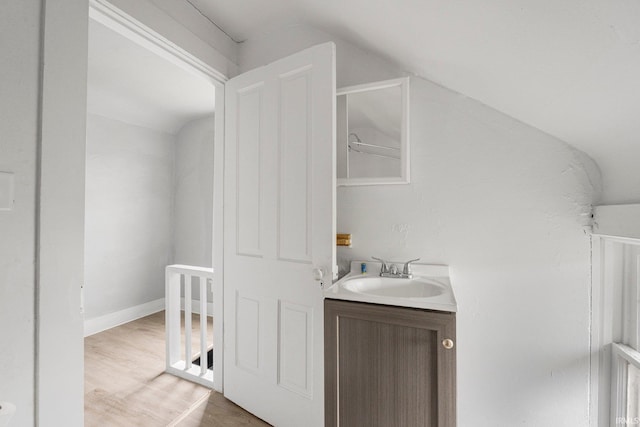 bathroom with vanity, wood finished floors, and lofted ceiling