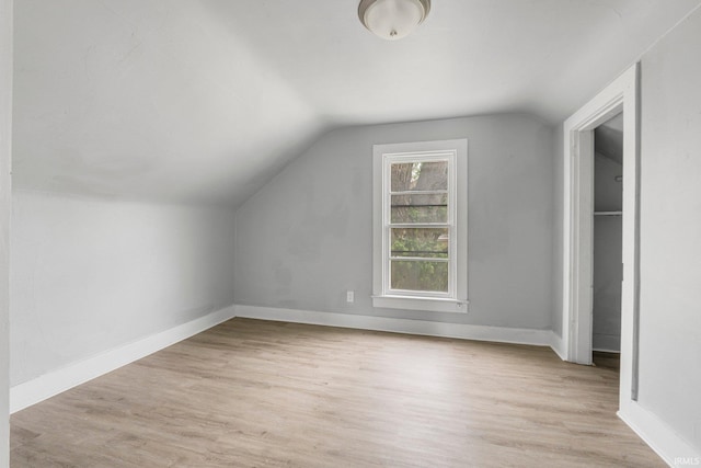 additional living space with light wood-type flooring, baseboards, and lofted ceiling
