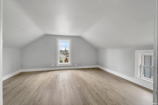 additional living space with baseboards, wood finished floors, and lofted ceiling
