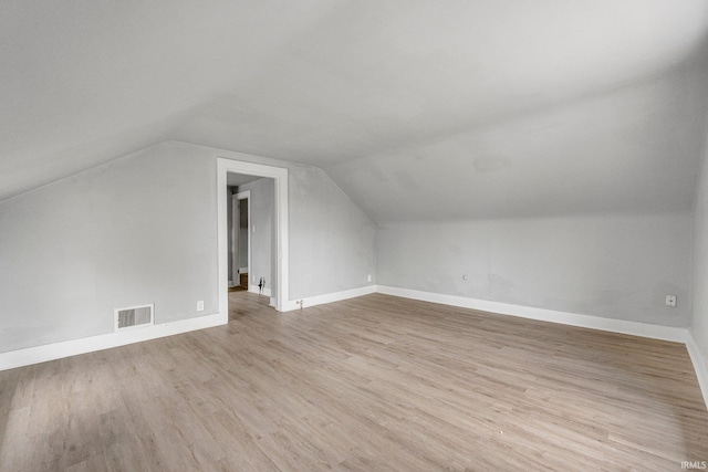 bonus room with baseboards, visible vents, light wood-style flooring, and vaulted ceiling