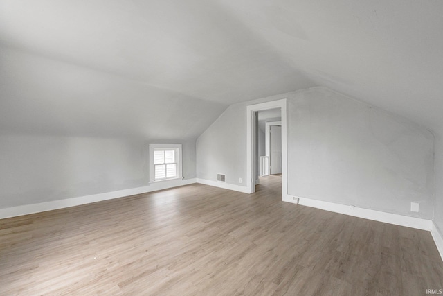 bonus room with baseboards, vaulted ceiling, wood finished floors, and visible vents