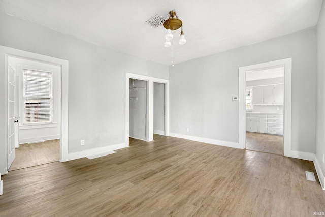 unfurnished bedroom with light wood-style floors, baseboards, and multiple windows