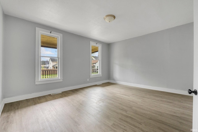 empty room featuring baseboards, visible vents, and wood finished floors