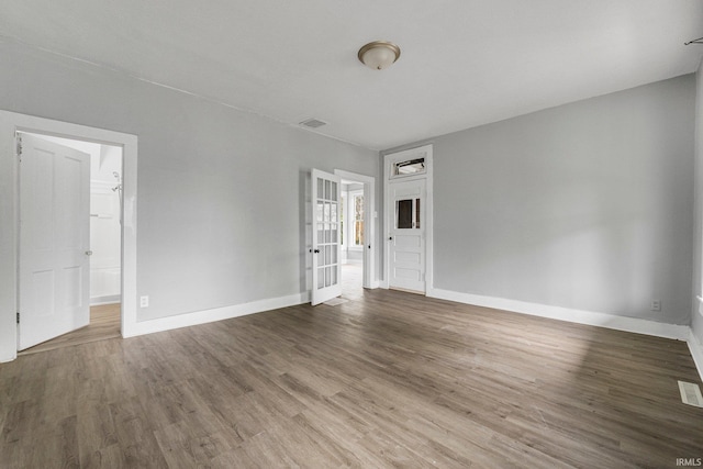 spare room with baseboards and wood finished floors