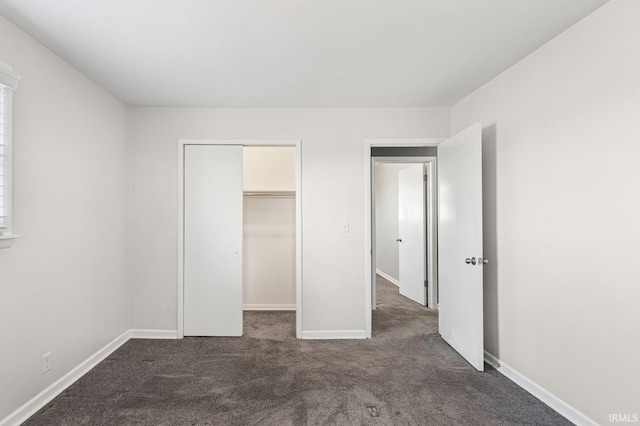 unfurnished bedroom featuring dark carpet, baseboards, and a closet