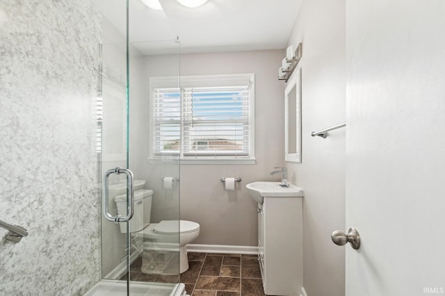 bathroom with toilet, a stall shower, baseboards, and vanity