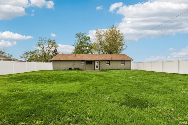 rear view of property featuring a yard and a fenced backyard