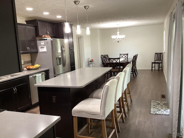 kitchen with appliances with stainless steel finishes, a breakfast bar, light countertops, light wood-style flooring, and a center island