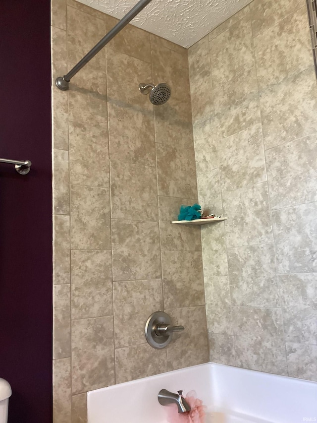 bathroom with a textured ceiling and shower / bath combination