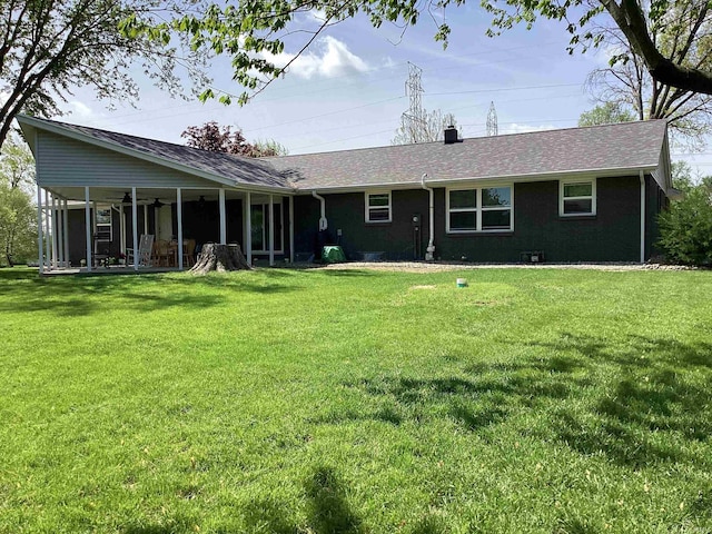 back of house featuring a yard, ceiling fan, a chimney, and a shingled roof