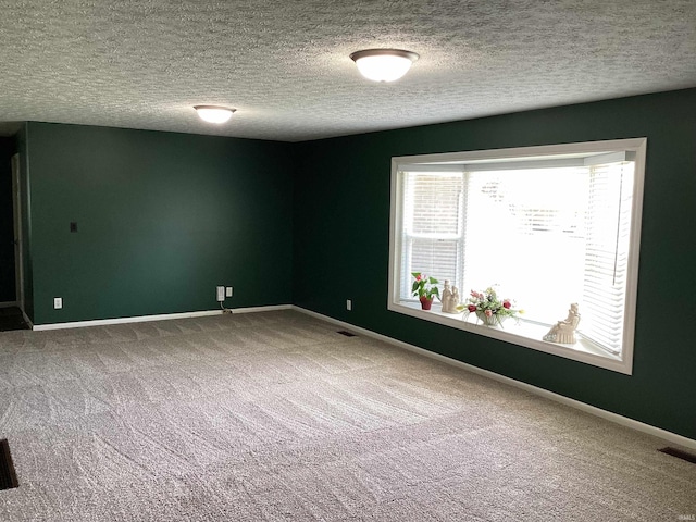 carpeted spare room featuring a textured ceiling, baseboards, and visible vents