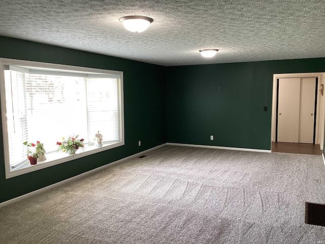 unfurnished room featuring carpet floors, baseboards, a textured ceiling, and visible vents