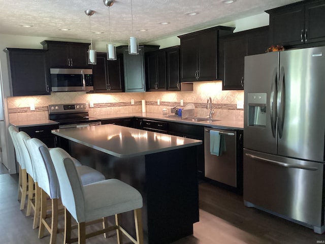 kitchen with a sink, dark cabinetry, a kitchen island, and stainless steel appliances