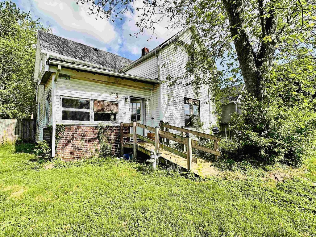back of property featuring a chimney, a wooden deck, brick siding, fence, and a yard