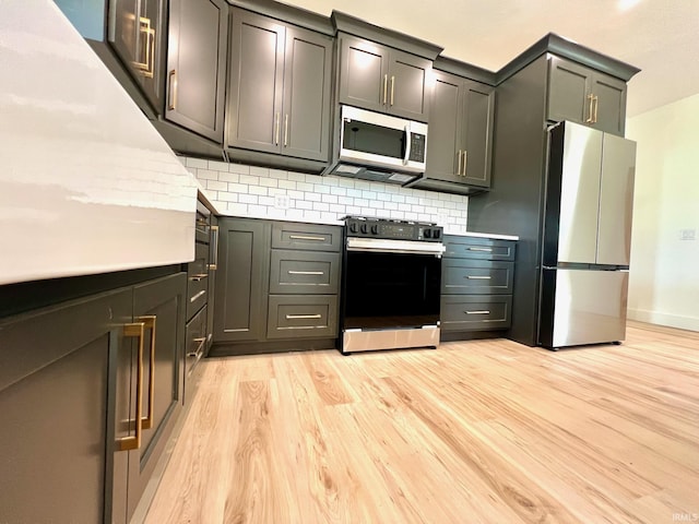 kitchen with light countertops, appliances with stainless steel finishes, tasteful backsplash, and light wood-style flooring
