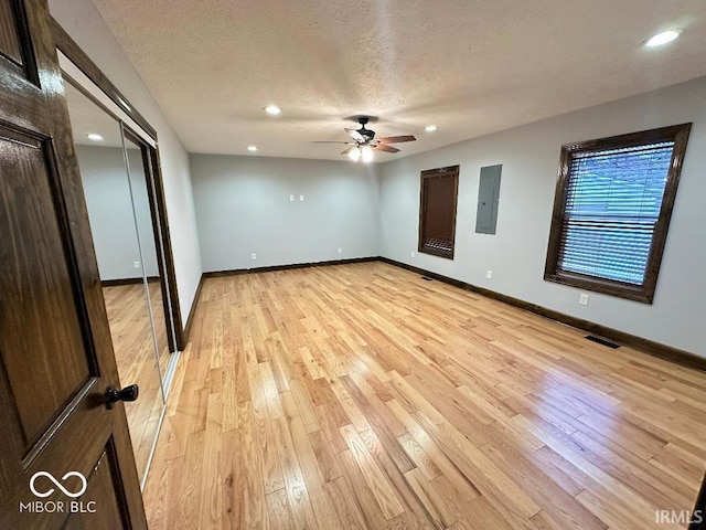empty room featuring a ceiling fan, light wood-style floors, visible vents, and electric panel