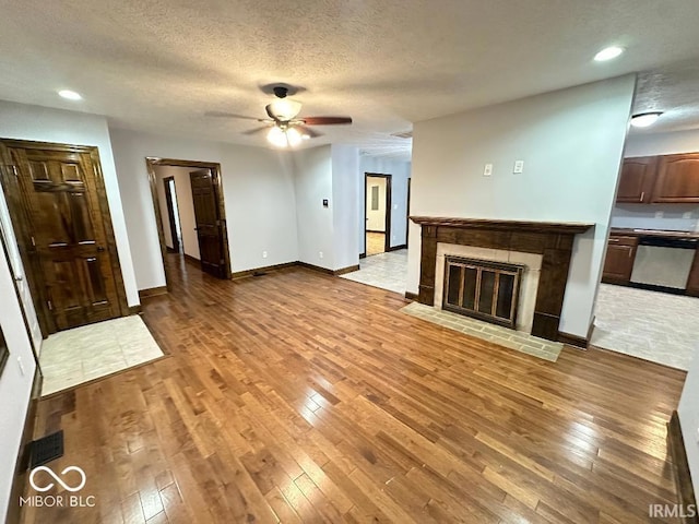 unfurnished living room featuring a fireplace with flush hearth, baseboards, recessed lighting, a ceiling fan, and light wood finished floors