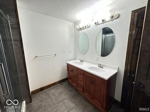 full bath featuring double vanity, a sink, a textured ceiling, and baseboards