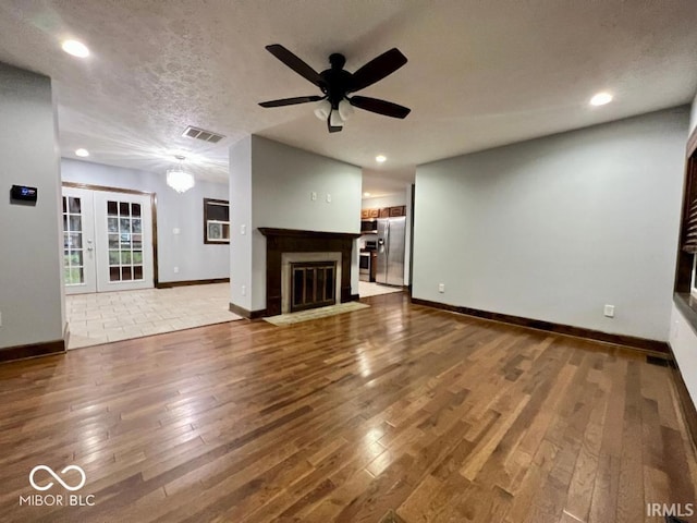 unfurnished living room with a ceiling fan, visible vents, baseboards, wood-type flooring, and recessed lighting