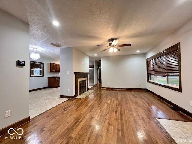unfurnished living room featuring a ceiling fan, visible vents, baseboards, light wood finished floors, and recessed lighting